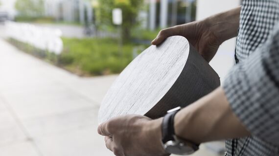 Person holding circular aluminum billet material.